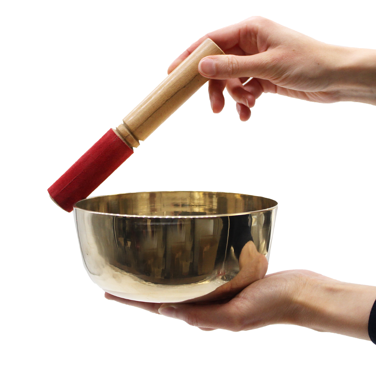 Gold singing bowl held by a hand with a wooden mallet featuring a red cushion on a white background
