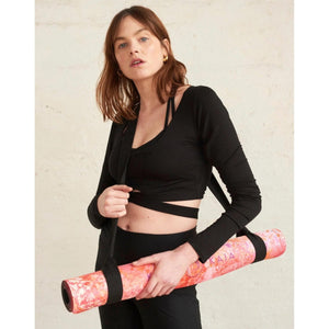 Kati Kaia artist yoga mats rolled up in pink and orange with carrying strap held by woman in black fitness wear