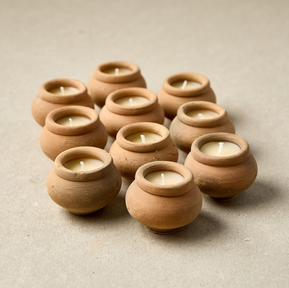 Terracotta pots with candles on a beige background