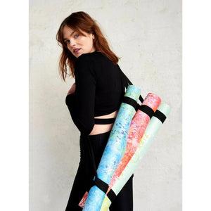 Woman carrying three colourful Kati Kaia artist yoga travel mats with vibrant artistic designs