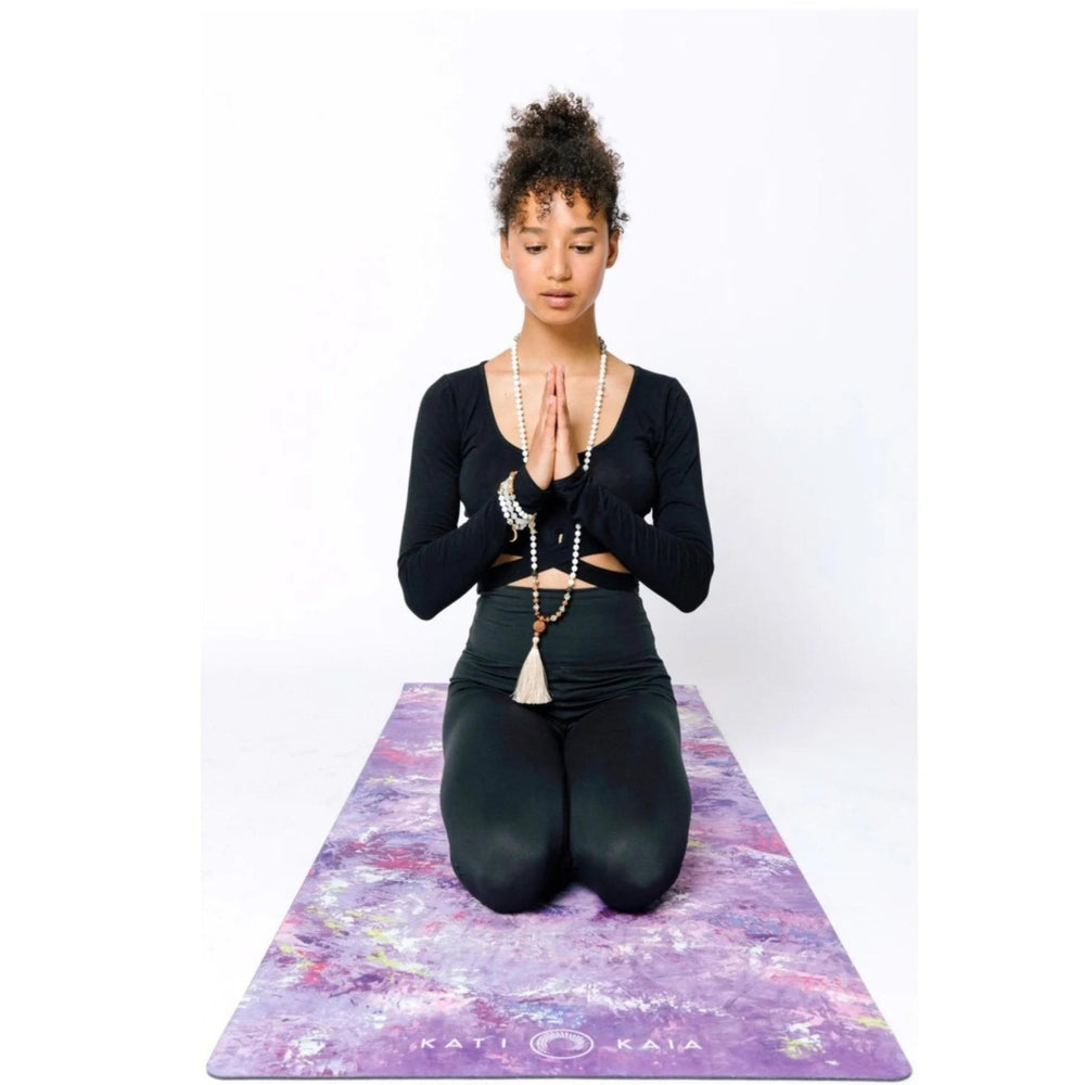 Kati Kaia artistic yoga mat in purple with floral design used by woman meditating in black activewear