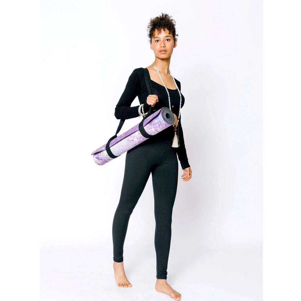 Woman holding artistic yoga mat by Kati Kaia rolled and carried with black strap