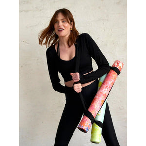 Woman carrying two colourful Kati Kaia stylish travel yoga mat UK rolled up with straps