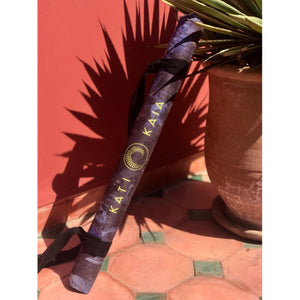Rolled Melete Blue touring yoga mat by Kati Kaia with carrying strap against terracotta tiles and plant pot