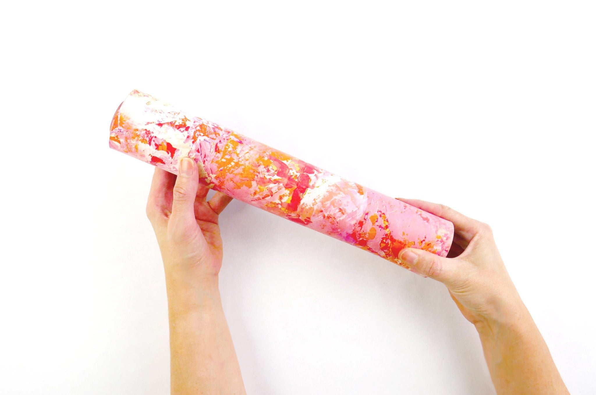 Hands holding a rolled up Kati Kaia Erytheia yoga pad with pink and orange floral design