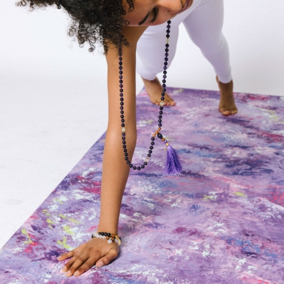 Kati Kaia artistic yoga mat with purple abstract design used by a person in white leggings for yoga practice