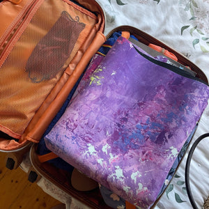 Folded Circe Purple Travel Mat by Kati Kaia packed inside a suitcase ready for travel