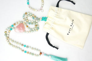 Kati Kaia Crystal Mala Necklace with turquoise and natural beads next to branded drawstring pouch