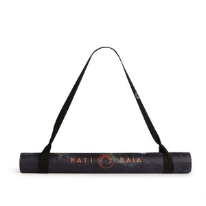 Kati Kaia portable yoga mat for travel rolled up with black carrying strap on white background