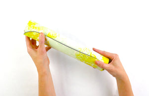 Kati Kaia yoga mat bag holding a rolled yellow and white yoga mat made from natural rubber