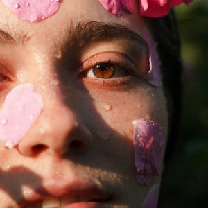 Close-up of face with pink flower petals and water drops promoting Kati Kaia natural skincare tonic
