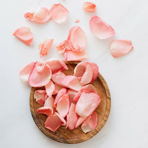 Natural pink rose petals on wooden plate symbolising Kati Kaia natural skincare tonic ingredients